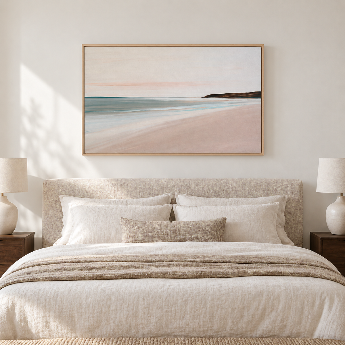 Tableau chambre en cadre chêne clair, paysage de plage rose poudré accroché au-dessus d'un lit aux draps crème
