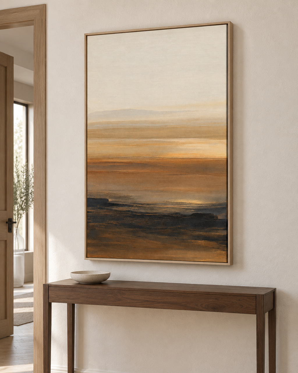 Paysage abstrait ocre et crème en cadre chêne clair accroché au-dessus d'une console en bois dans une entrée