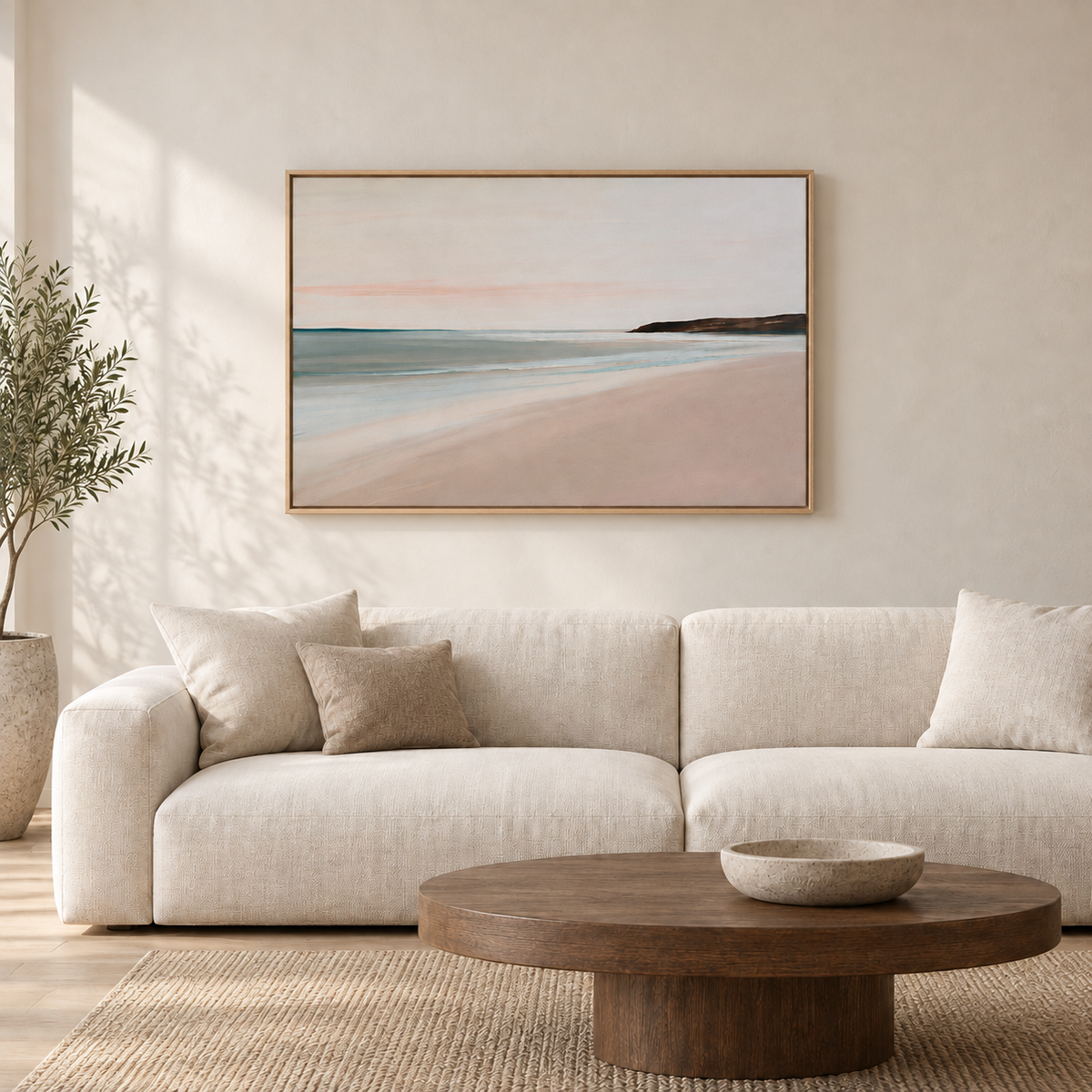 Grand tableau déco salon en cadre chêne clair, bord de mer rose au-dessus d'un canapé blanc et d'une table basse