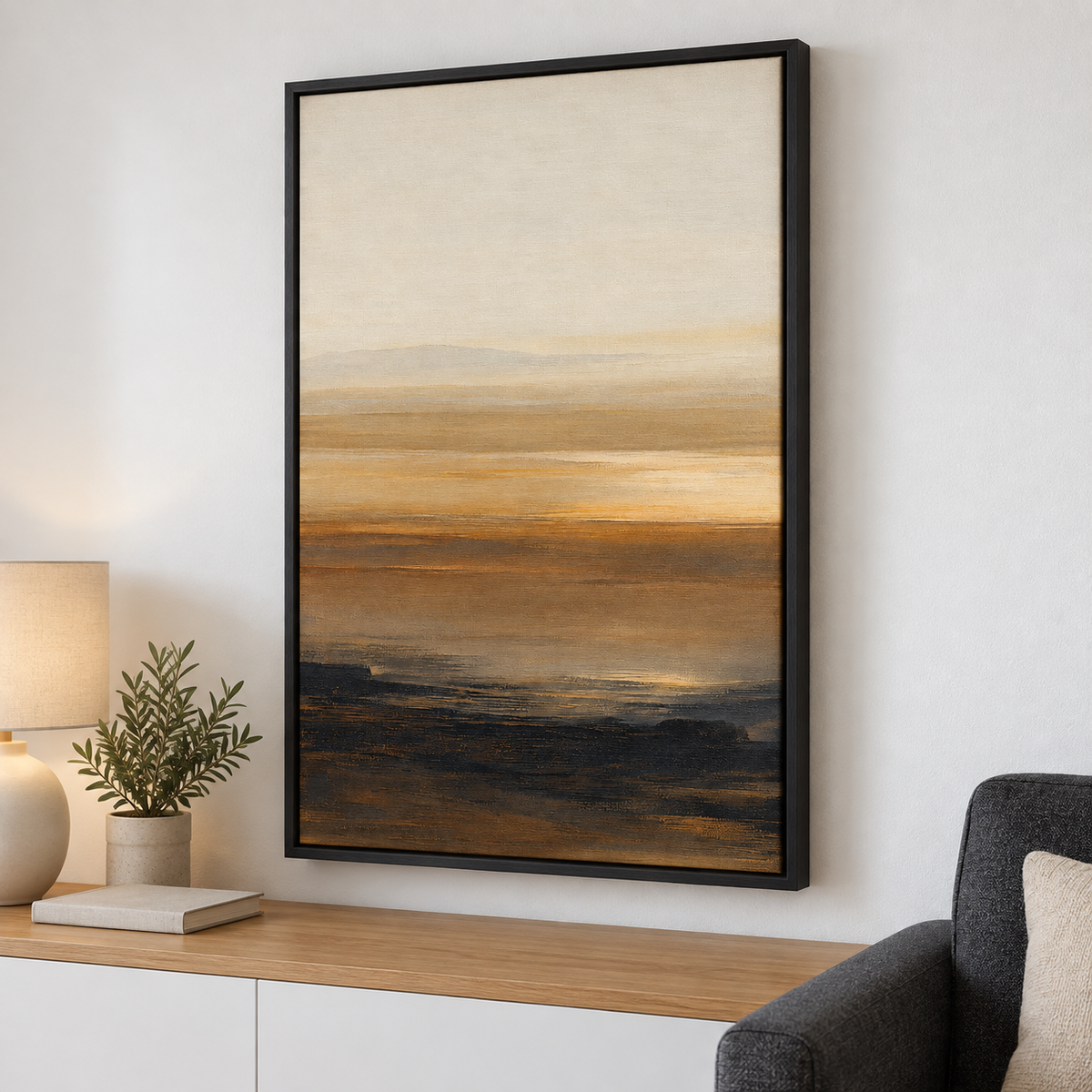 Grand tableau déco salon en cadre noir, paysage ocre et doré au-dessus d'un meuble blanc et d'un fauteuil gris