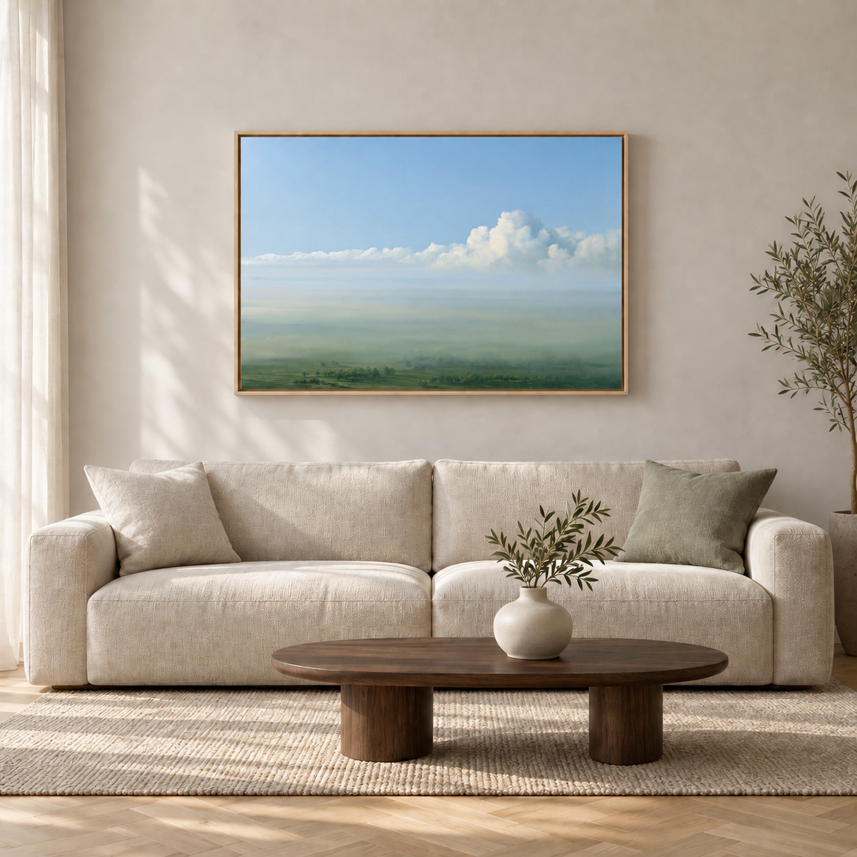Tableau déco salon en cadre chêne clair, ciel bleu et campagne verte au-dessus d'un canapé blanc et table basse