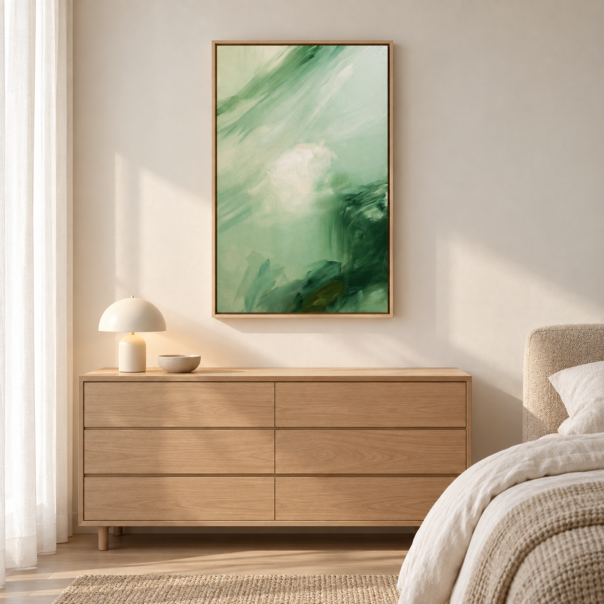 Tableau chambre en cadre chêne clair, peinture abstraite verte au-dessus d'une commode en bois clair près du lit