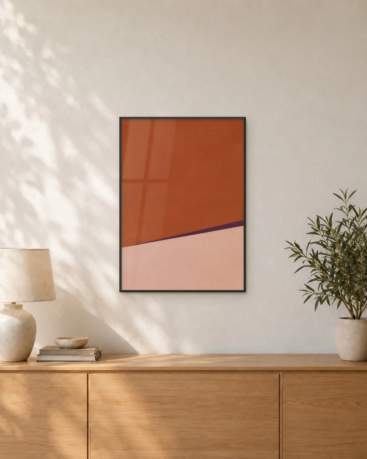 Affiche déco salon terracotta et rose poudré encadrée en noir au-dessus d'un buffet en chêne