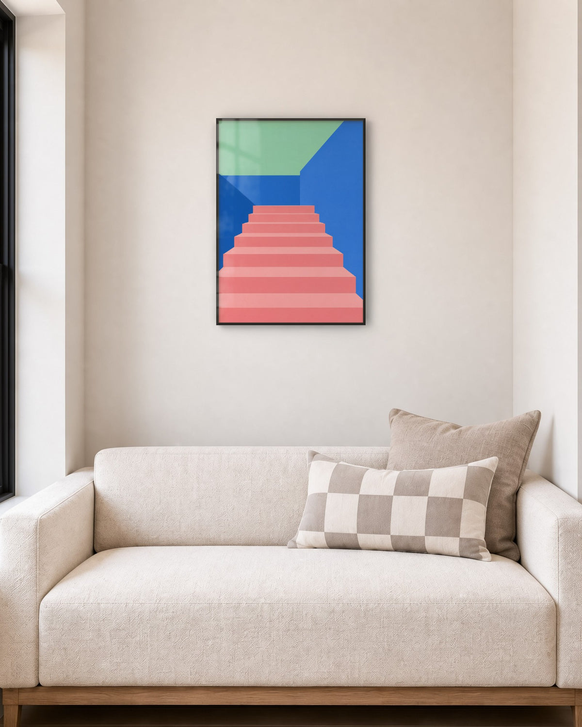 Affiche escalier rose entre des murs bleu vif et vert d’eau, cadre noir, au-dessus d’un petit canapé écru