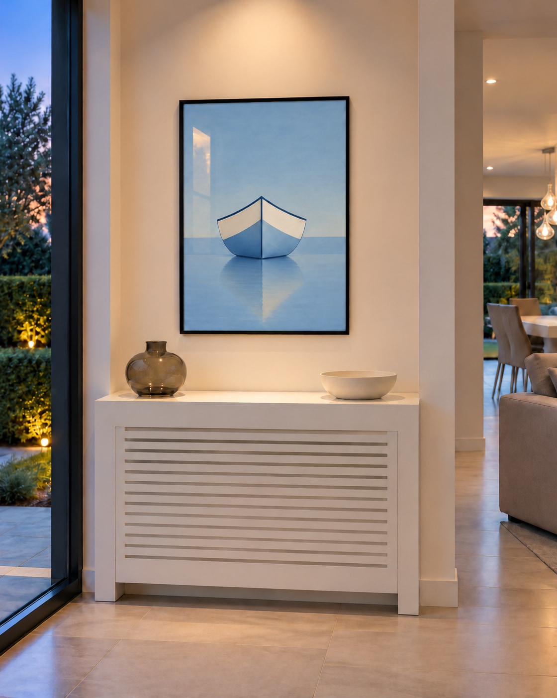 Affiche entrée barque bleue et son reflet encadrée en noir au-dessus d’un cache-radiateur blanc