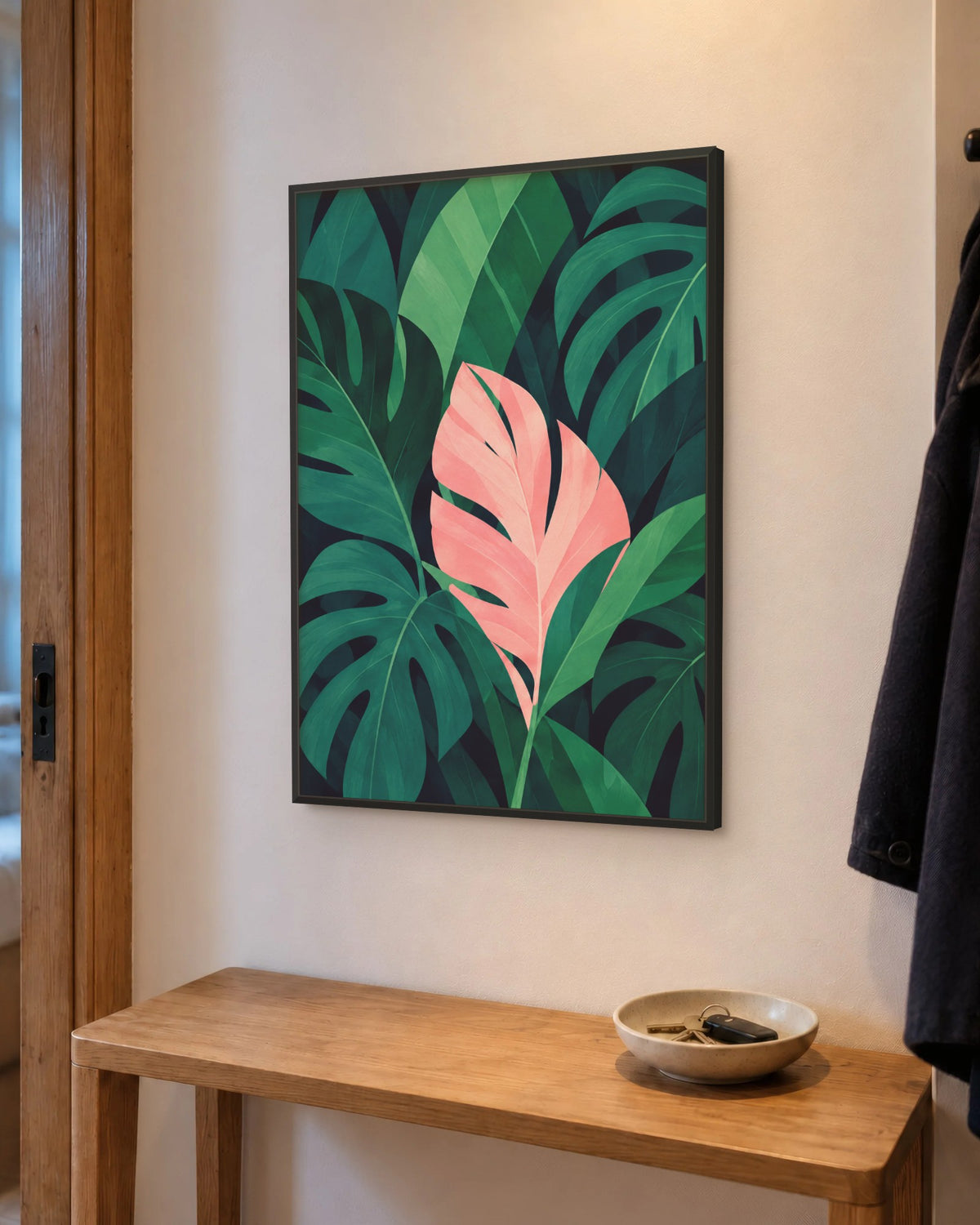 Affiche entrée feuillage tropical vert encadrée en noir au-dessus d'une console étroite en chêne