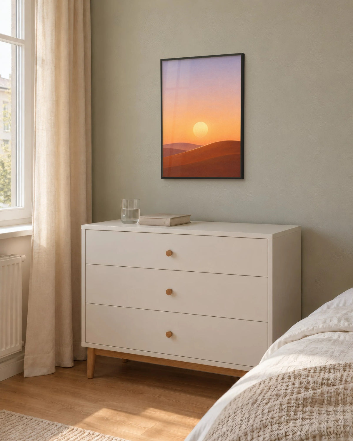 Affiche chambre désert orange et lavande encadrée en noir sur un mur sauge, au-dessus d'une commode