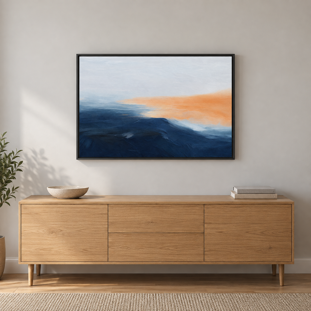 Tableau déco salon en cadre noir : paysage abstrait bleu et orange au-dessus d'un meuble bas en bois clair