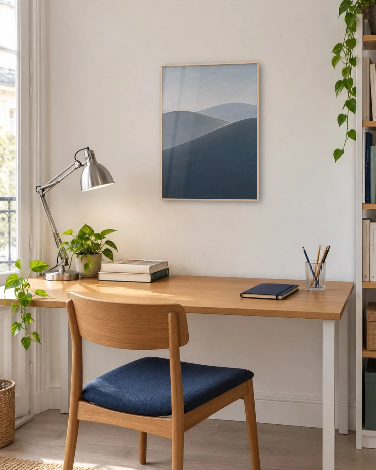Affiche bureau collines bleu ardoise en cadre chêne clair au-dessus d'un bureau près d'une fenêtre