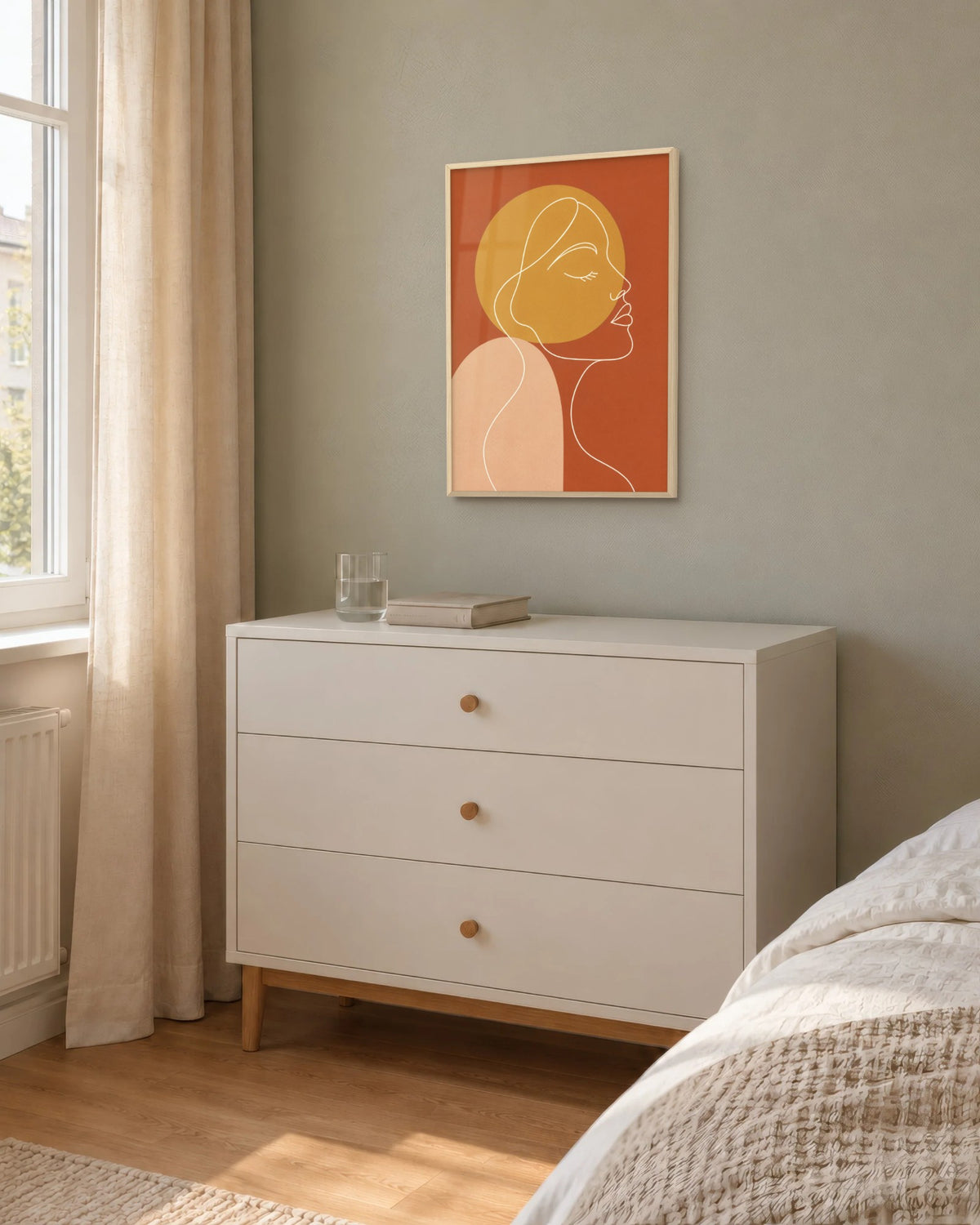 Affiche chambre visage line art en cadre chêne clair sur un mur sauge, au-dessus d'une commode