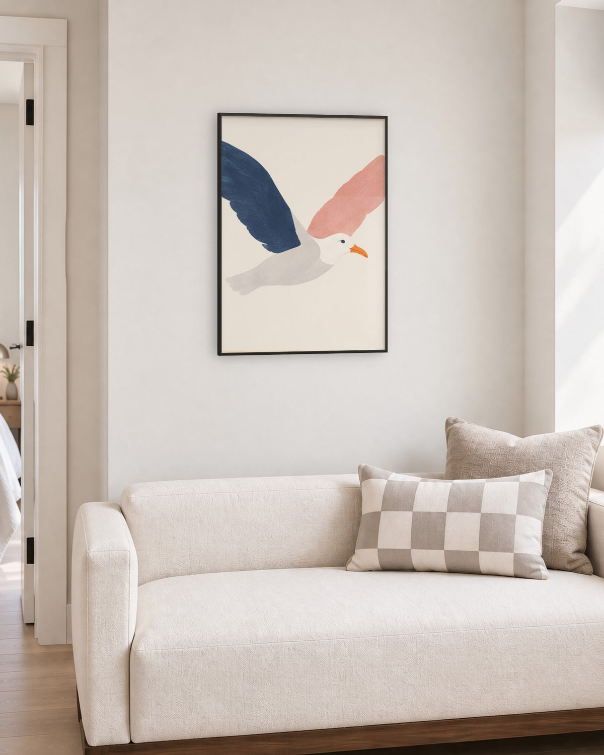 Affiche mouette bleu marine et rose sur fond crème, cadre noir, coin salon au canapé écru sur socle noyer