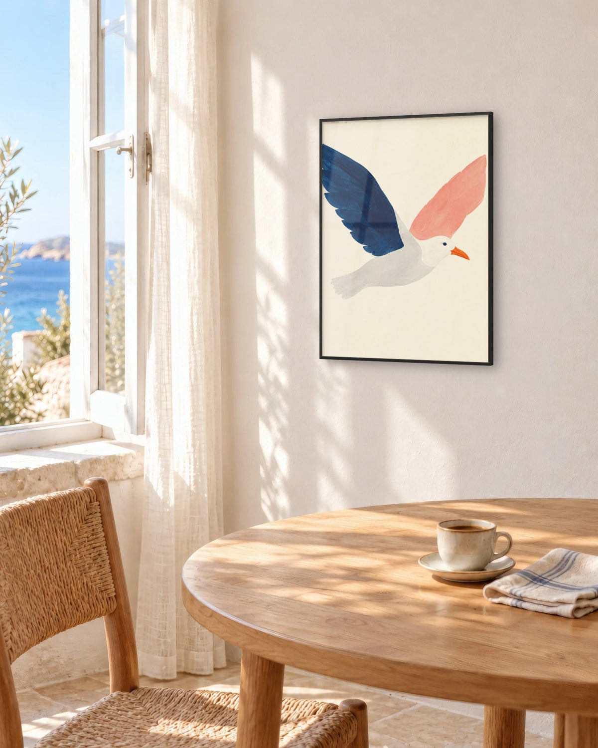 Affiche déco salle à manger mouette bleu marine en cadre noir au-dessus d'une table face à la mer
