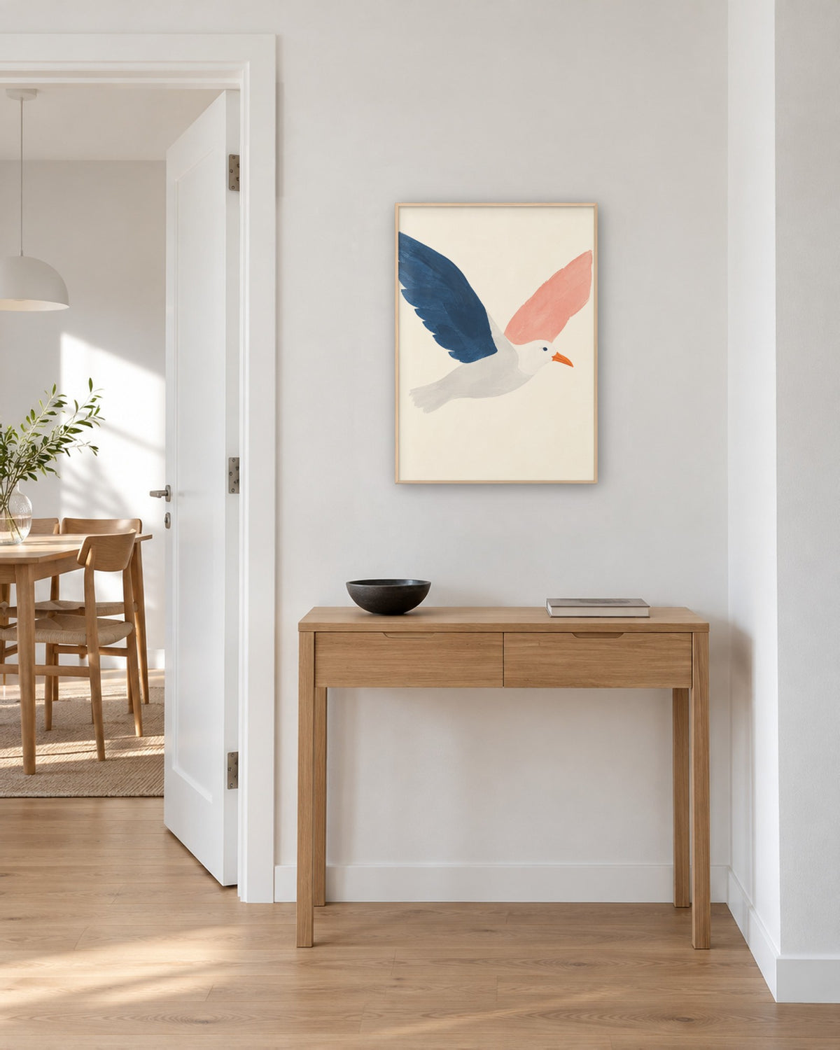 Affiche mouette bleue et rose sur fond crème en cadre chêne clair au-dessus d’une console d’entrée