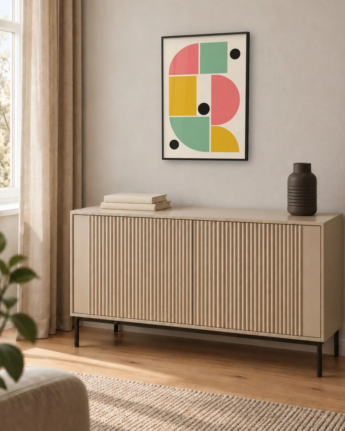 Affiche déco salon Bauhaus rose et vert en cadre noir au-dessus d'un buffet beige à rainures