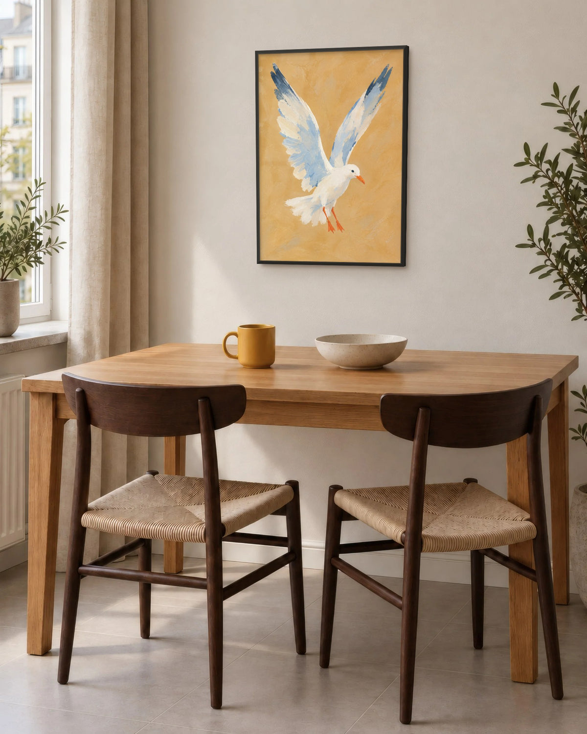 Affiche salle à manger ocre et bleu ciel en cadre noir au-dessus d'une table en chêne et de deux chaises