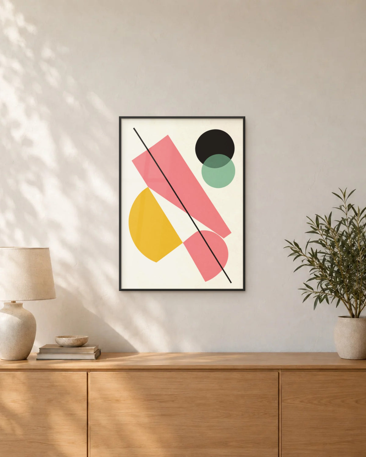 Affiche déco salon géométrique rose et jaune en cadre noir au-dessus d'un buffet en chêne
