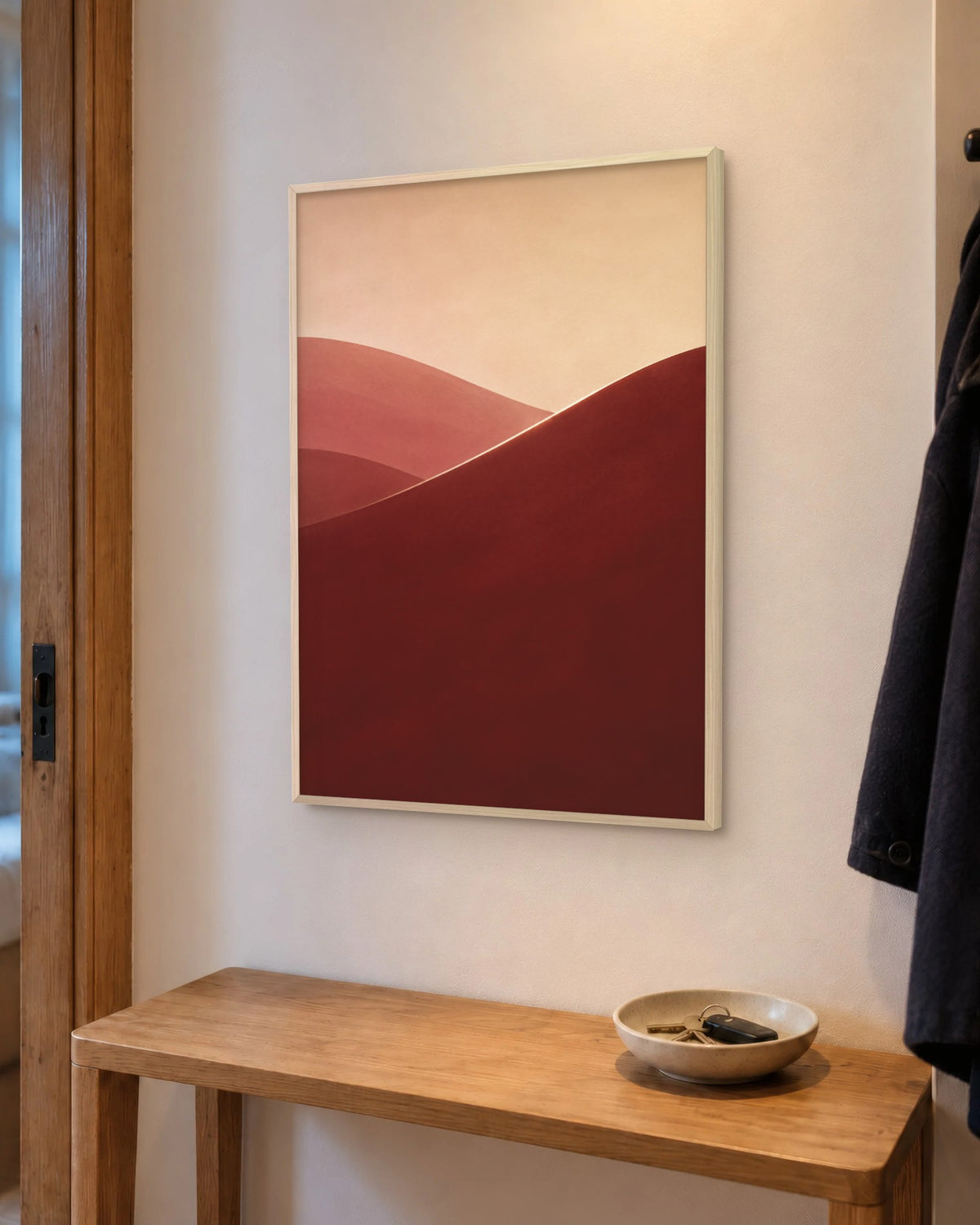 Affiche entrée dunes bordeaux et rose en cadre chêne clair au-dessus d'une console en chêne