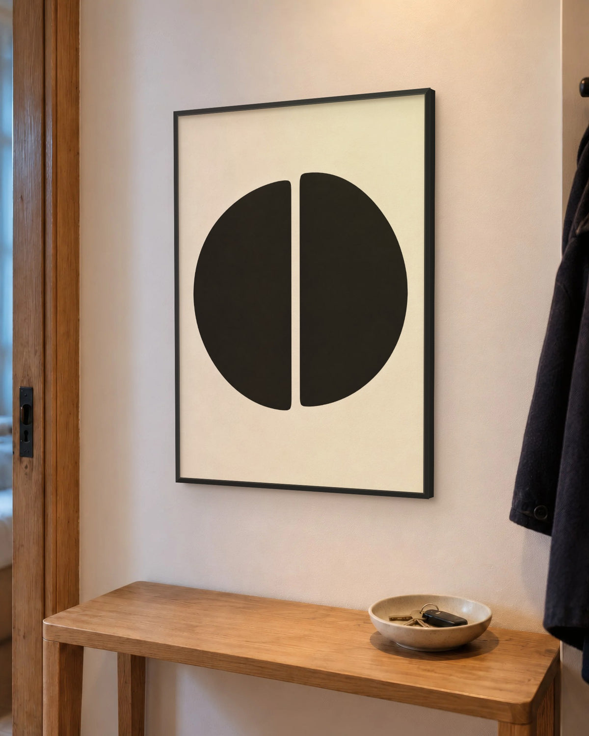 Affiche entrée minimaliste noir et crème encadrée en noir au-dessus d'une console en chêne